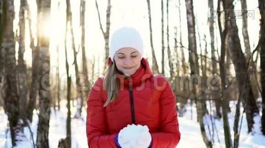 迷人的年轻女子在阳光明媚的冬季公园，玩雪，玩得开心，微笑。 慢动作视频