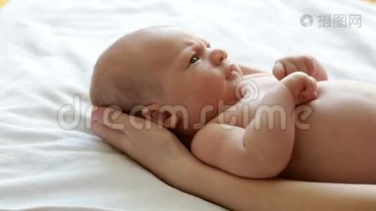 初生婴儿躺在母亲手中，看着视频