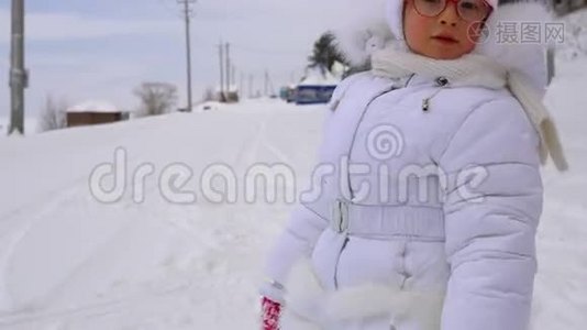 女孩在白雪覆盖的道路上奔跑。 冬季公园儿童假期活动。视频