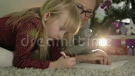 祖母和孙女躺在圣诞树附近的地板上。视频