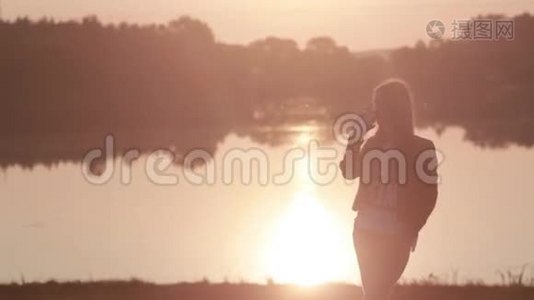 小女孩看着河上美丽的日出，喝着热气腾腾的咖啡视频