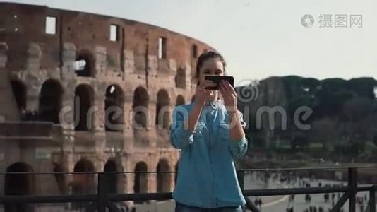 一位年轻的旅游女性在意大利罗马的斗兽场拍照，智能手机微笑着，笑着。 慢动作。视频