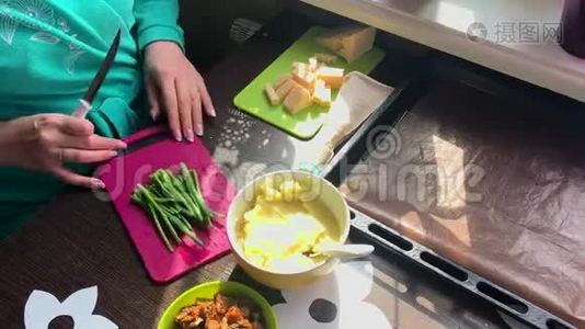 女人在切割板上切葱。 接下来的盘子是奶酪、土豆泥和炸蘑菇。视频