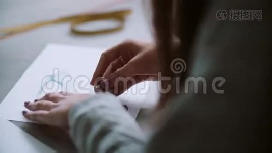 年轻女子用蓝鞋素描擦在纸上的背面。 设计师坐在桌子旁，开发布局。 4K视频