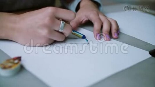女人坐在桌子旁，拿着铅笔，在纸上画出鞋子的着色草图。 右滑，相机绕一圈。 4K视频