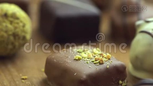 手工制作的巧克力糖果落在木制背景上，美味的糖果在缓慢运动的UHD。视频