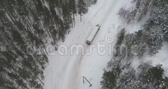 卡车在雪林的冬季乡村道路上行驶。 空中镜头。视频