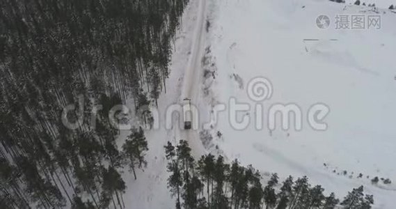 卡车在雪林的冬季乡村道路上行驶。 空中镜头。视频