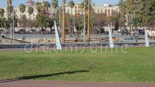 年轻女性穿着一件红色手提包的裙子，穿在巴塞罗那码头公园的背景上，带着智能手机走路，然后见面视频