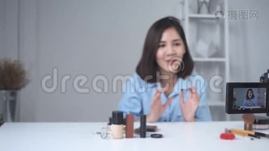 快乐微笑的亚洲女人或美女博主用画笔和相机录制视频，并在家挥手。视频