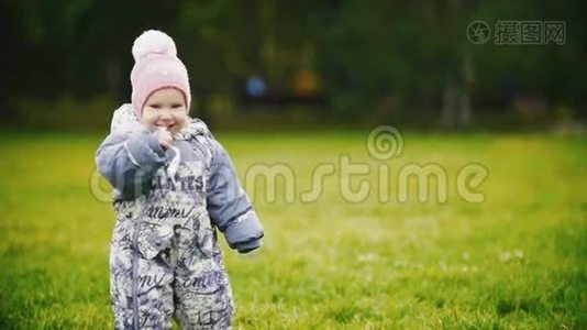 幸福的家庭：在秋天公园散步的母子小女孩：一个婴儿在嚼一张纸，慢动作视频