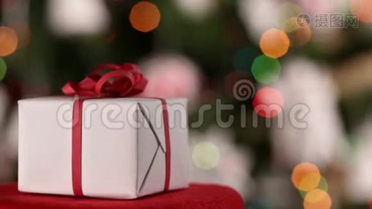 圣诞礼物在圣诞树上闪烁的灯光前旋转视频