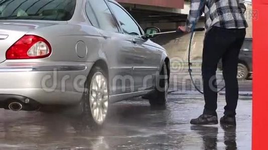 男人用高压洗衣机喷水冲洗他的车。 洗车自助服务..视频