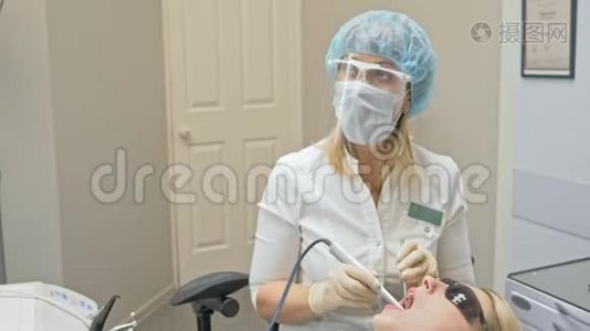 医生用特殊的口腔检查数字微相机检查牙齿。 医生和助理保护工作视频
