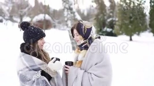 在冬季公园里，两个穿着格子布的女孩在说话，微笑着喝茶视频
