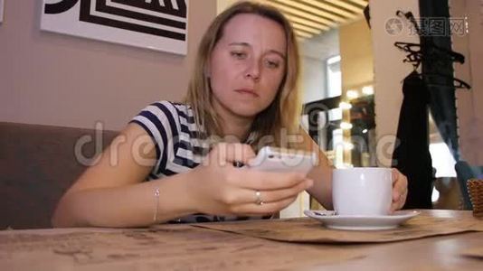 一个女人正在咖啡馆里用电话和一杯咖啡视频