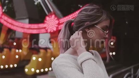 戴眼镜的年轻姑娘，在游乐园里抚摸着秋千附近的头发视频
