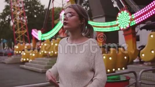 迷人的女孩戴着眼镜，在游乐园里抚摸着秋千附近的头发视频