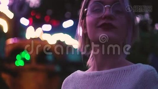 一个戴眼镜的漂亮女孩在附近的游乐园里摆姿势视频