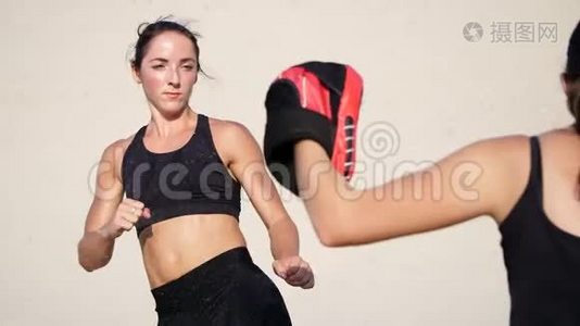 两个穿着黑色健身服的年轻女子，在荒无人烟的情况下，穿着一双运动服，锻炼踢腿，训练打架视频