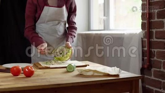 女性用手做皮塔和肉屑，并在厨房添加蔬菜。视频