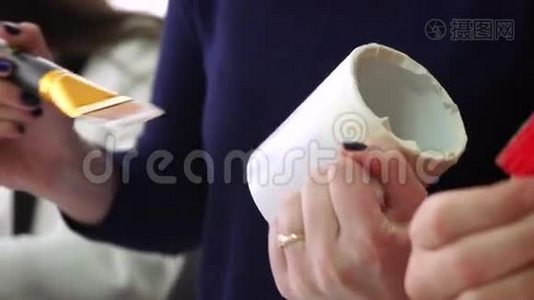 设计师用画笔绘制，并在白色陶瓷杯上油漆。视频