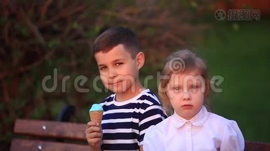 男孩吃冰淇淋，坐在长凳上，而女孩正在看。视频