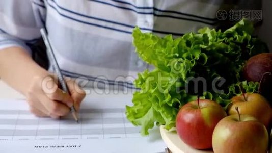 女人在满桌的水果和蔬菜上写饮食计划视频