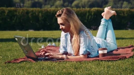 年轻女子拿着笔记本电脑在草地上放松视频