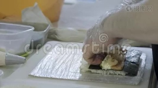 特写。做寿司厨师在厨房里准备面包卷。搓米饭和诺丽，切工件。使用日语视频