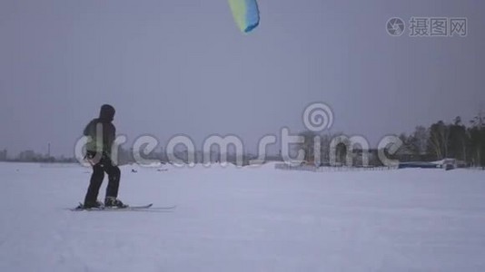 一个年轻人抓住了风筝的风，他被拉到了雪地上视频