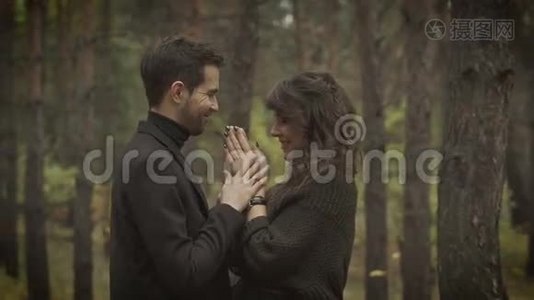 一对夫妇在森林里约会。 微笑的男人和女人站在树上，互相看着，微笑着视频