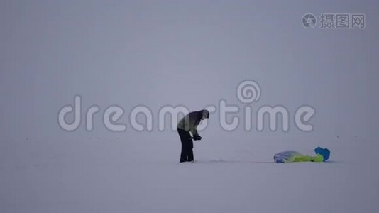 年轻人解开降落伞，爬在雪地上，4K视频