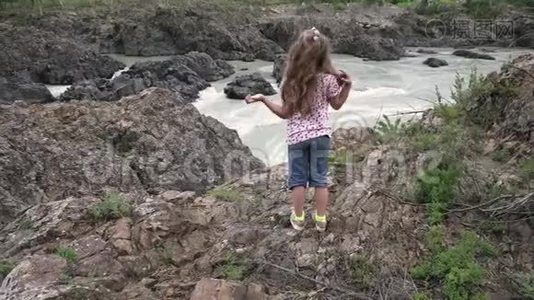 小女孩旅行者。 一个孩子站在山的背景下的山河悬崖边视频