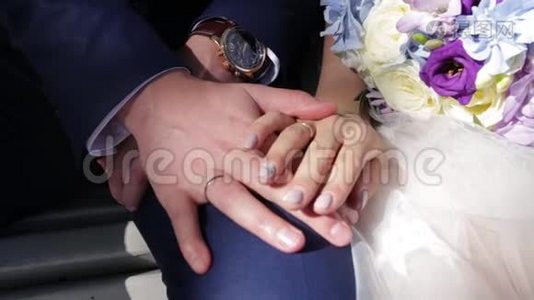 新婚夫妇`手里拿着结婚戒指。 新娘和新郎在鲜花或婚礼花束上戴着结婚戒指。 新婚夫妇视频