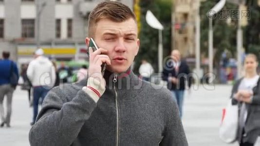 城市广场上一个年轻英俊的男人在手机上说话的肖像。视频