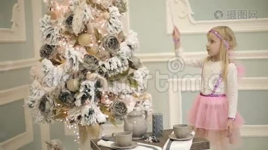 穿着粉红色翅膀仙女服装的小女孩蛊惑圣诞树。视频