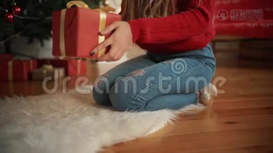 圣诞节，一个漂亮的女孩在树下发现了一件礼物。 概念：魔术，圣诞节，礼物，节日..视频