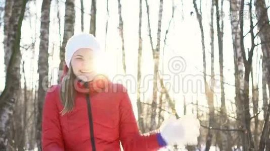美丽的年轻女子在阳光明媚的冬季公园里，打雪球，玩得开心，微笑。 慢动作。视频