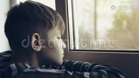 少年悲伤和孤独透过窗户看。 少年很沮丧视频