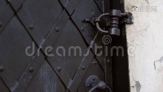 一种老式的黑色金属门，用覆盖板加固。视频