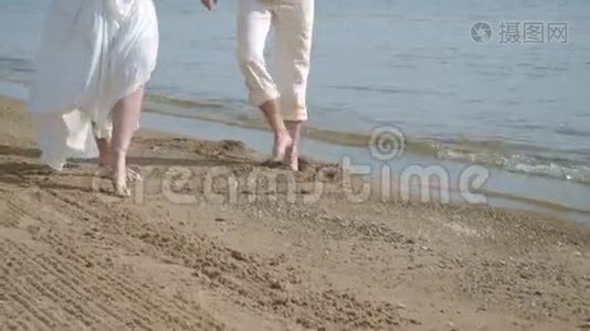 在海滩上玩得很开心的怀孕夫妇。 双脚在海滩上视频