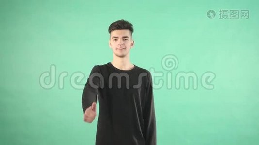 年轻男子微笑着竖起大拇指，被孤立在绿色的背景上视频