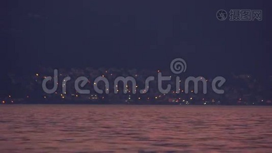 傍晚，美丽的海景，遥远的城市灯光，平静的水，迷人的风景，一艘小船航行视频