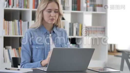 有颈部疼痛的疲惫年轻女子在做手提电脑视频