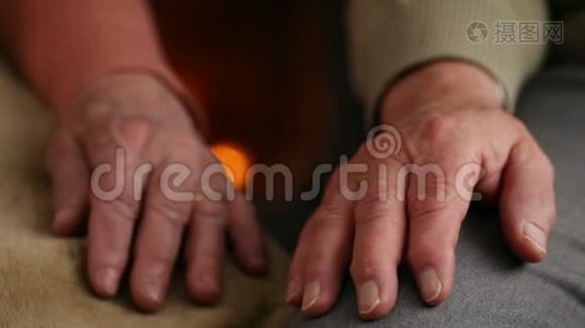 女人和男人的双手在壁炉前休息-老年概念视频