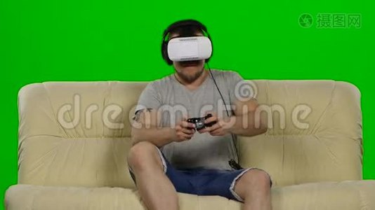 戴虚拟现实护目镜的人。 摄影棚，白色沙发。 绿色屏幕视频