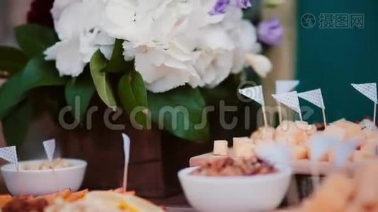 奶酪桌的近景。 花，切片奶酪，坚果，鸡蛋和西红柿在木板上。视频