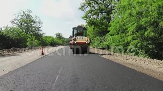 修复一条公路、压路机和沥青修整机，铺设一条新的新鲜沥青路面，覆盖在一条公路上视频