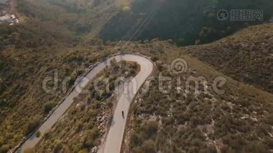 孤独的旅行者骑着摩托车在壮丽的山路上的无人机镜头视频